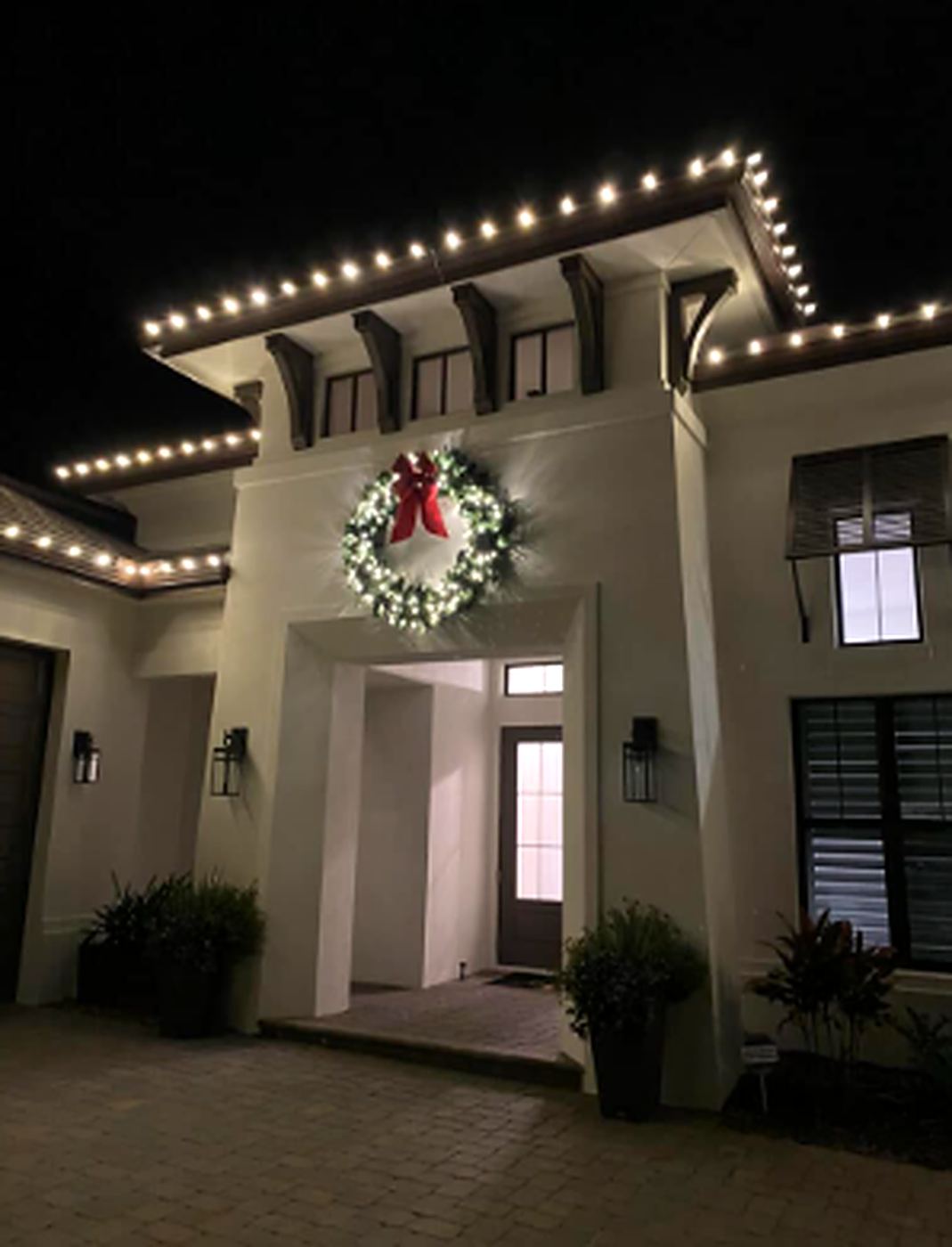 Commercial building entrance with lit wreath and roofline Christmas lighting