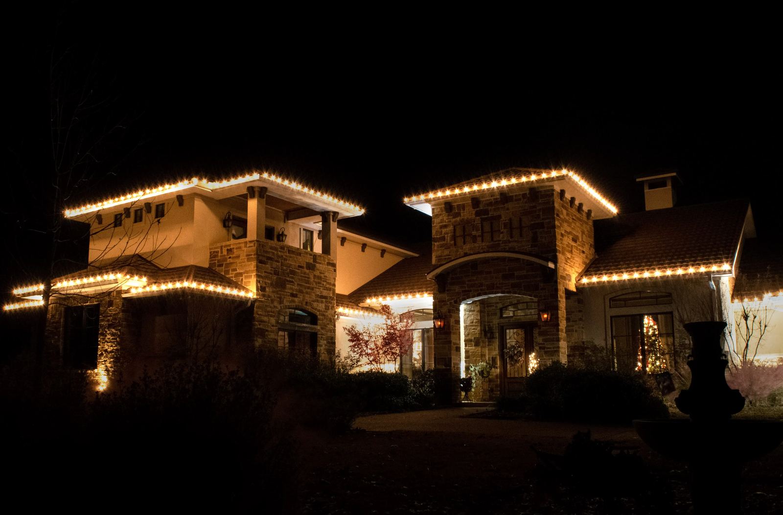 Commercial property with warm white roofline Christmas lighting on stone entry towers
