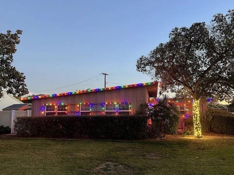 Ranch home roofline with multicolor lights and wrapped tree