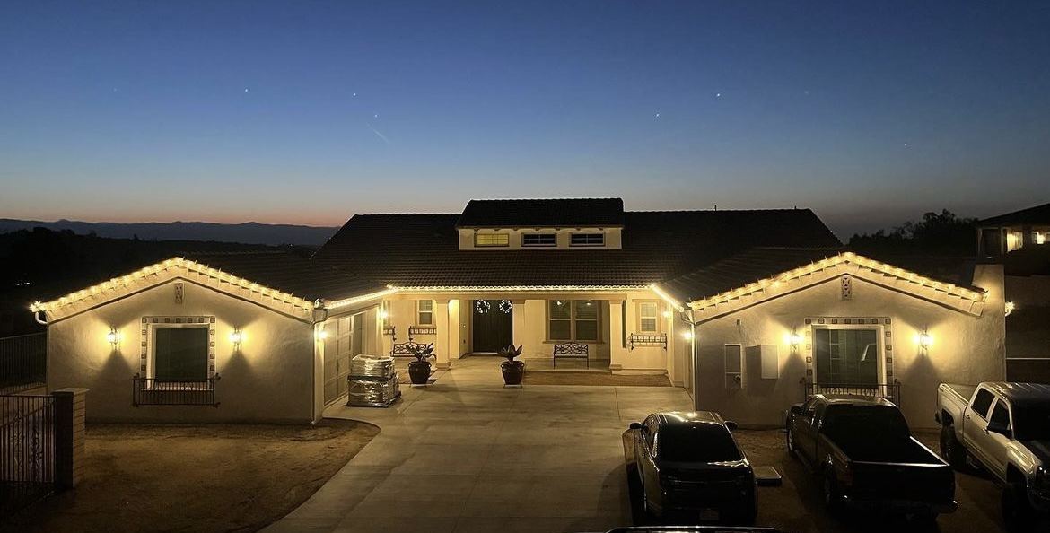 Ranch home with warm white roofline Christmas lighting at dusk