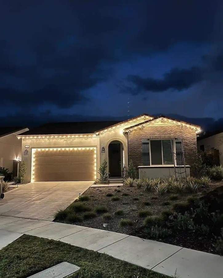 Christmas lighting installation on new construction home at dusk