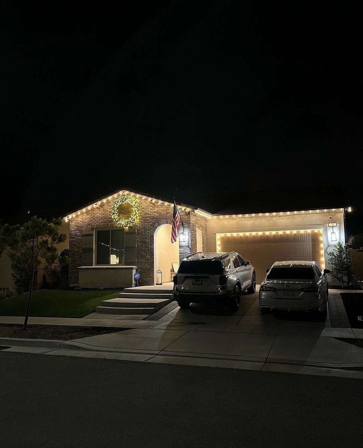 Single-story home with lit wreath and roofline lighting