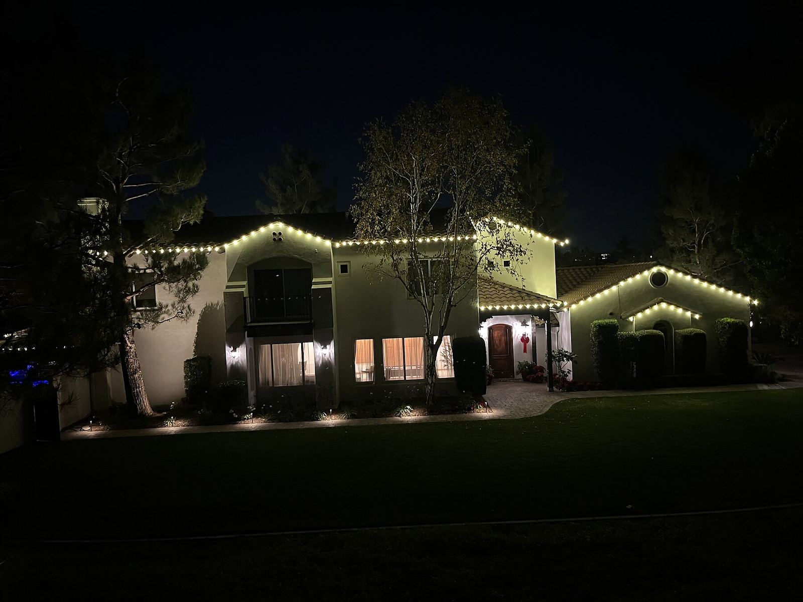Two story warm white front lawn night — Christmas light installation in Riverside, CA