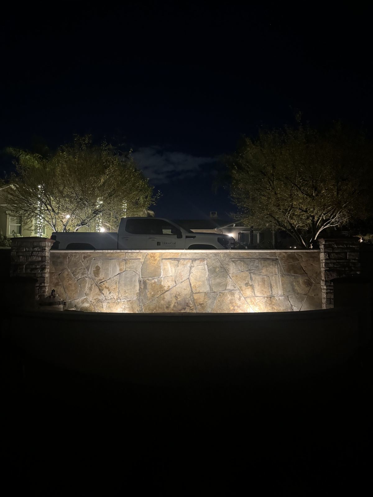 Monument wall entrance night — landscape lighting install in Riverside, CA
