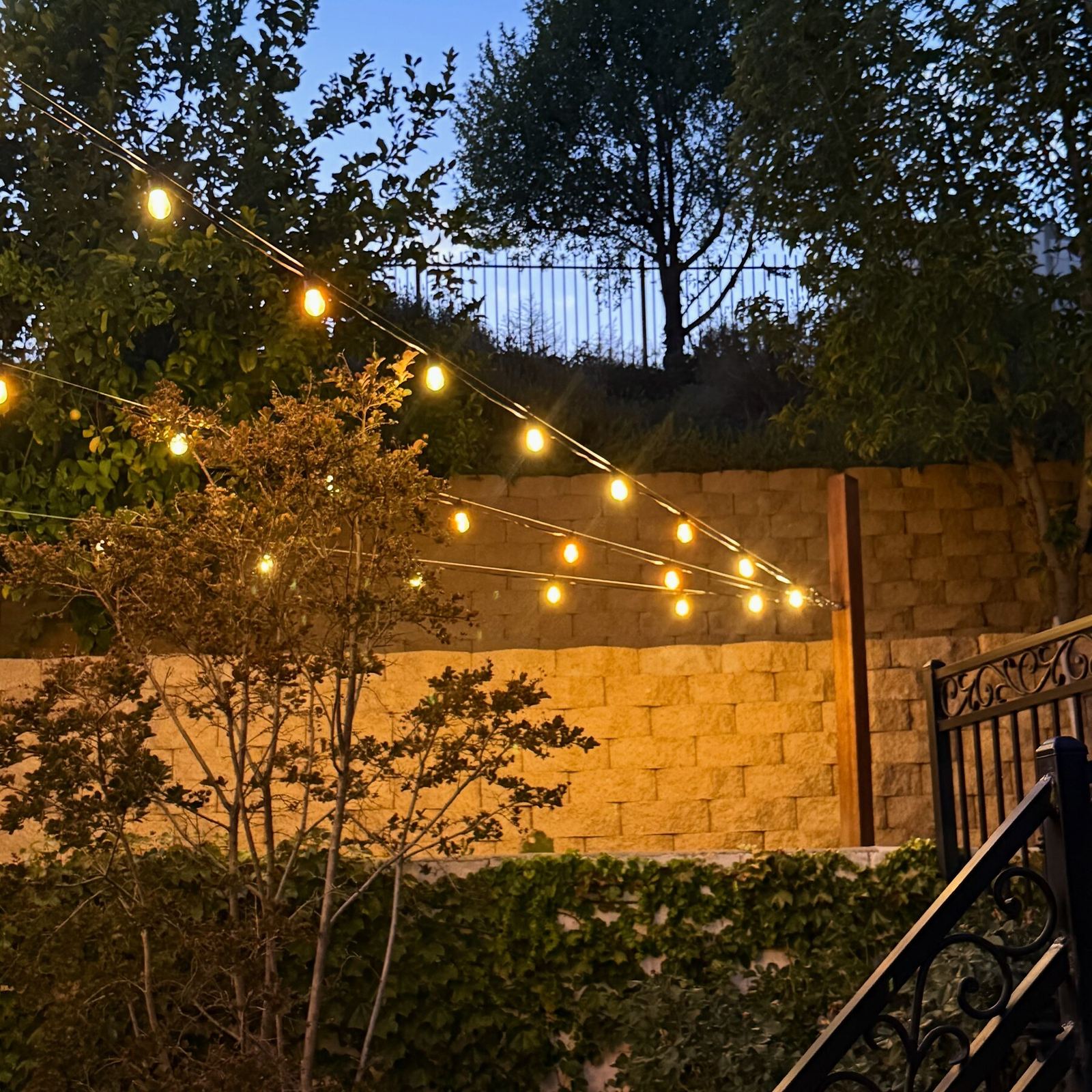 String lighting over patio with retaining wall at dusk