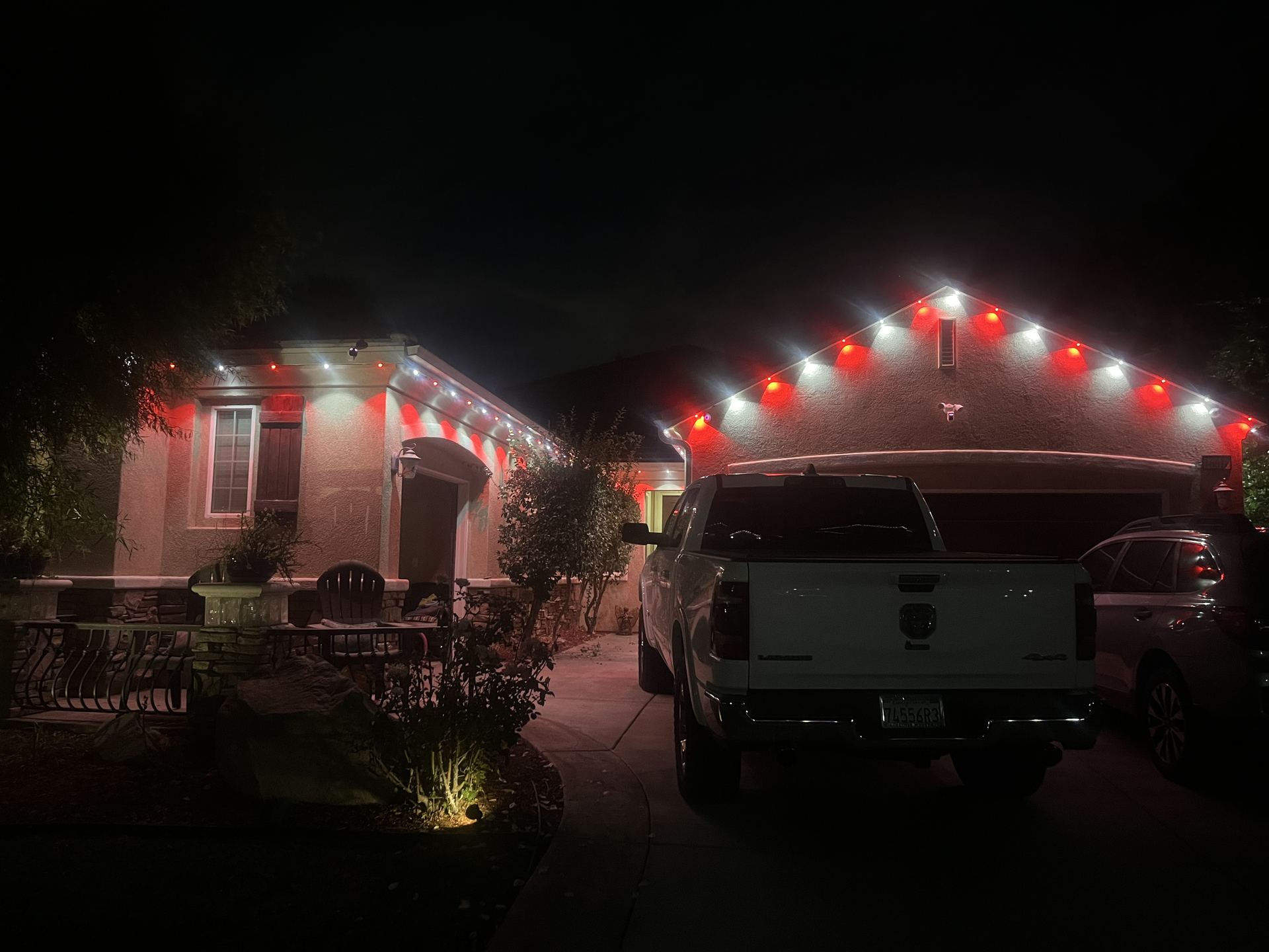Single-story home with red and white permanent roofline lighting over driveway