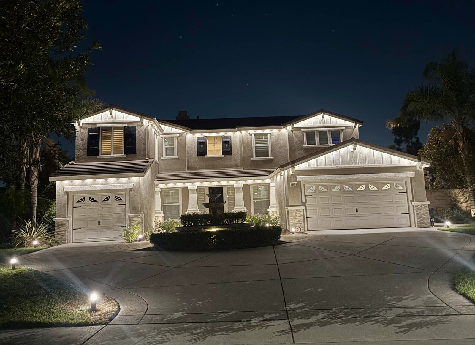 Permanent warm white roofline lighting on large estate with fountain and circular driveway