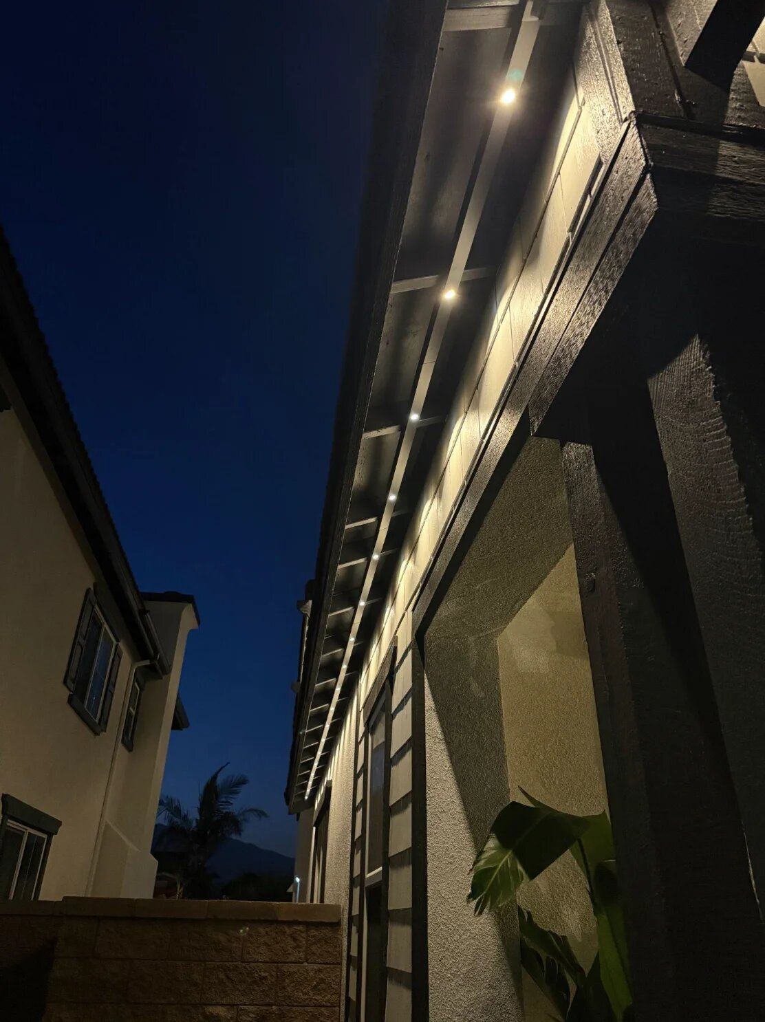 Permanent warm white lighting close-up along roofline at dusk
