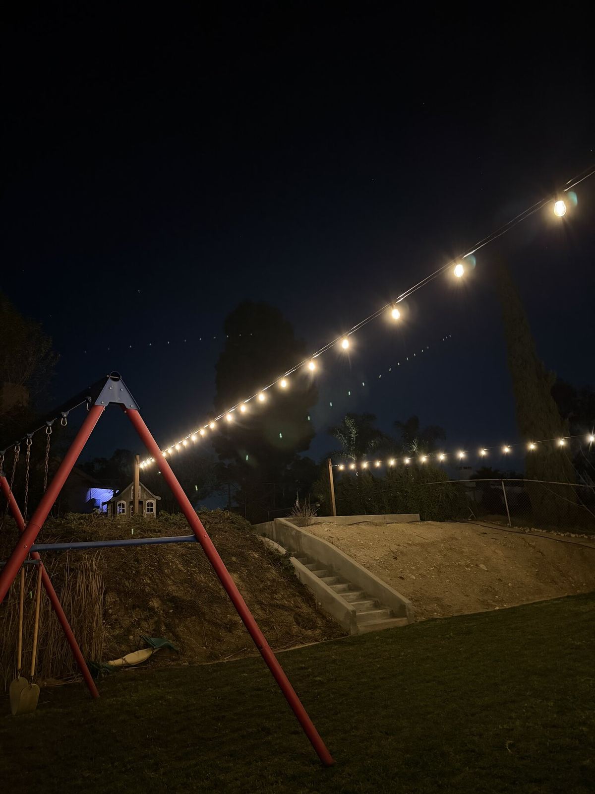 Backyard swingset hillside night — bistro & string lighting install in Riverside, CA