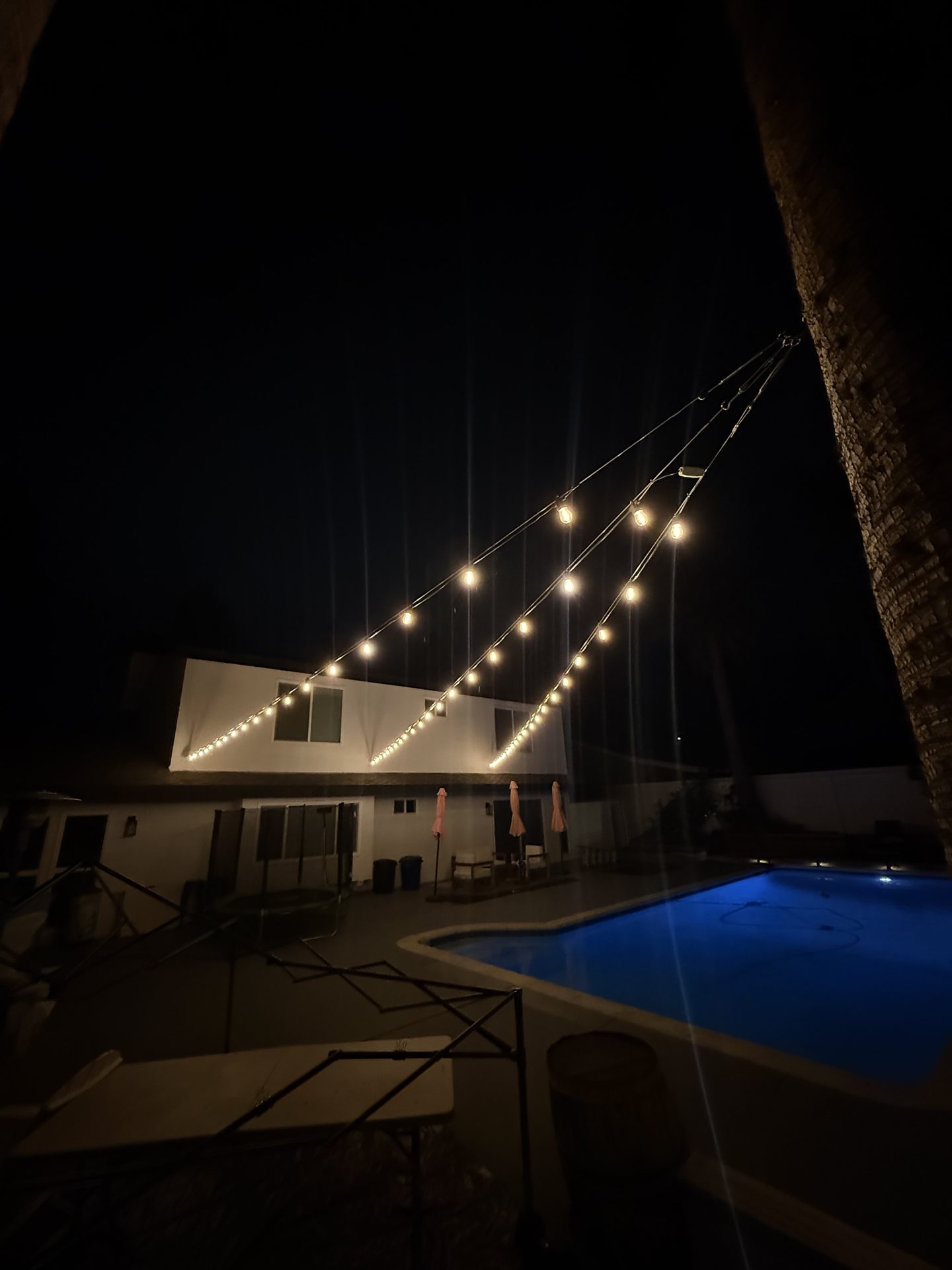 String lighting in diagonal lines over pool and house — bistro & string lighting install in Riverside, CA