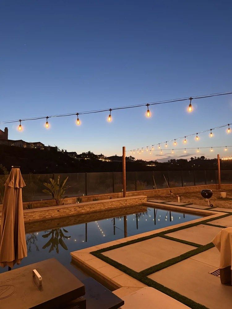 String lighting over pool at dusk with mountain view