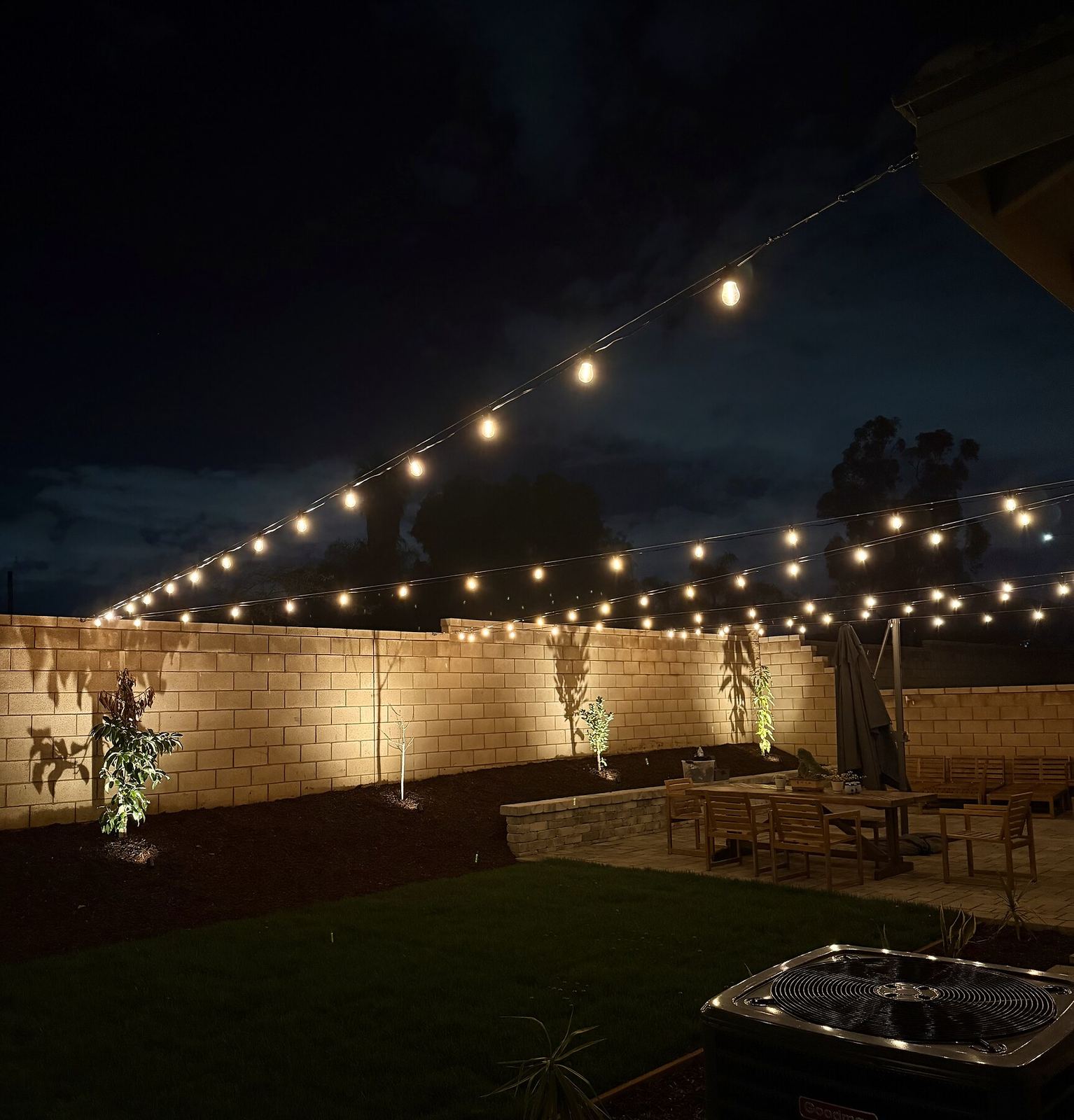 Backyard wall dining table night — bistro & string lighting install in Riverside, CA