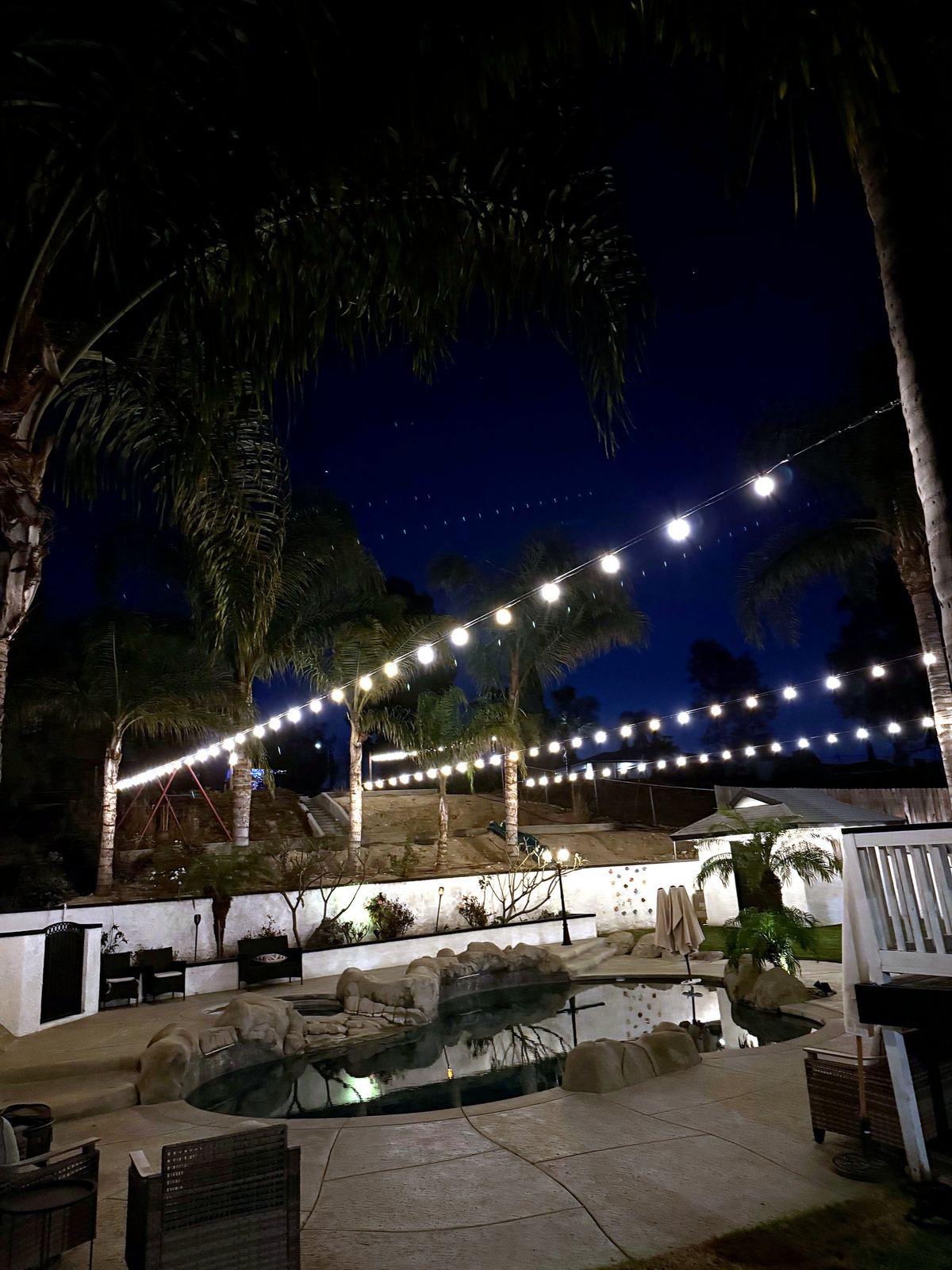 Dark backyard palms pool night — bistro & string lighting install in Riverside, CA