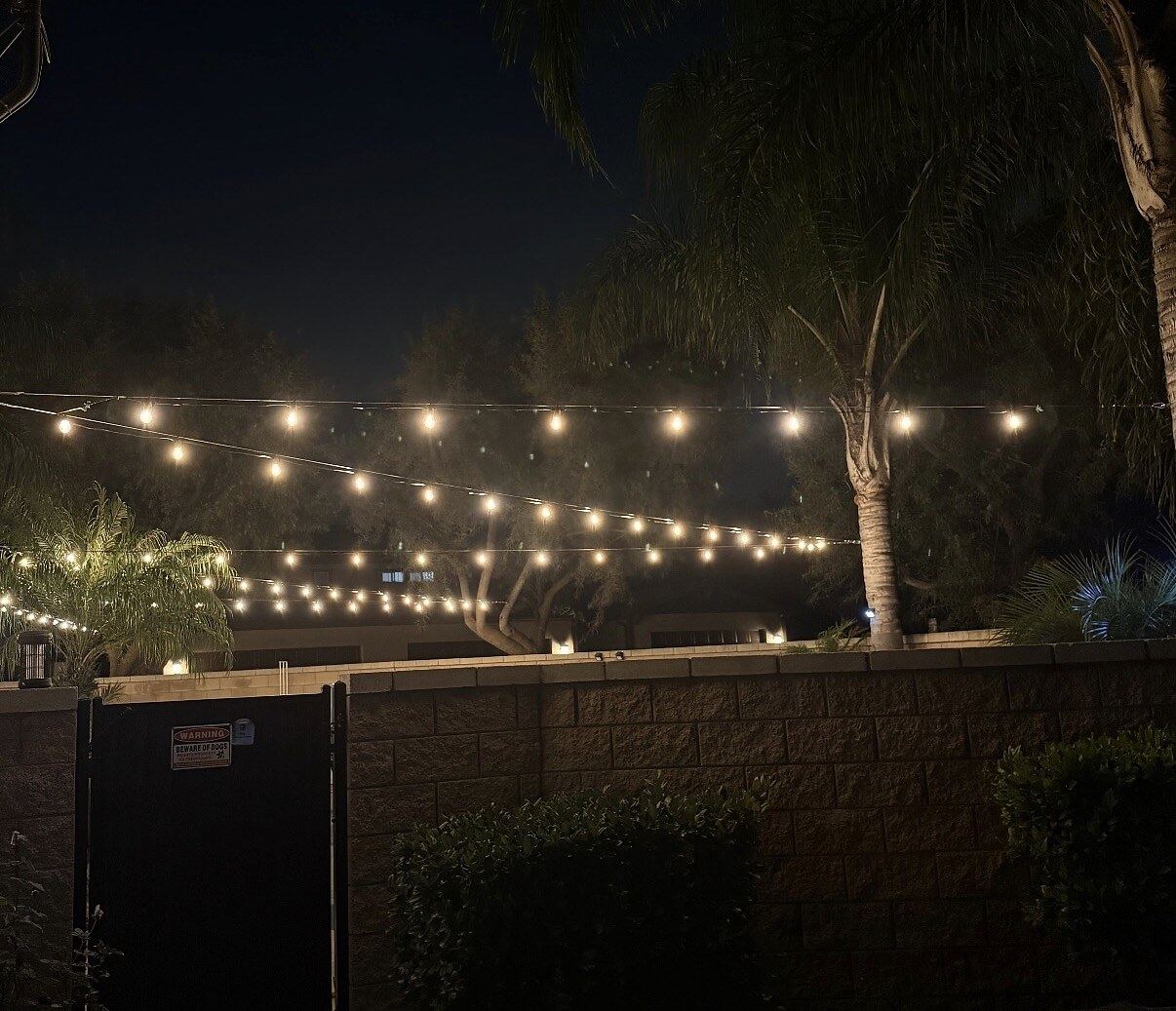 Fence warning sign dusk — bistro & string lighting install in Riverside, CA